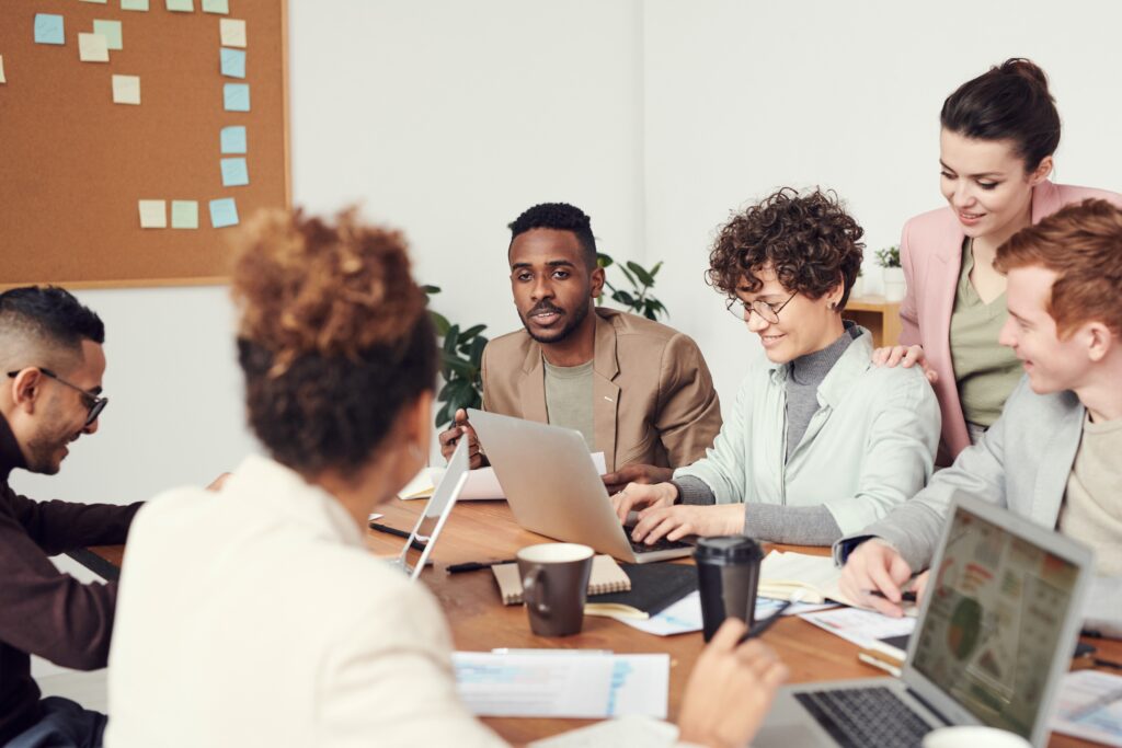 A group of people sitting around a table with laptops.