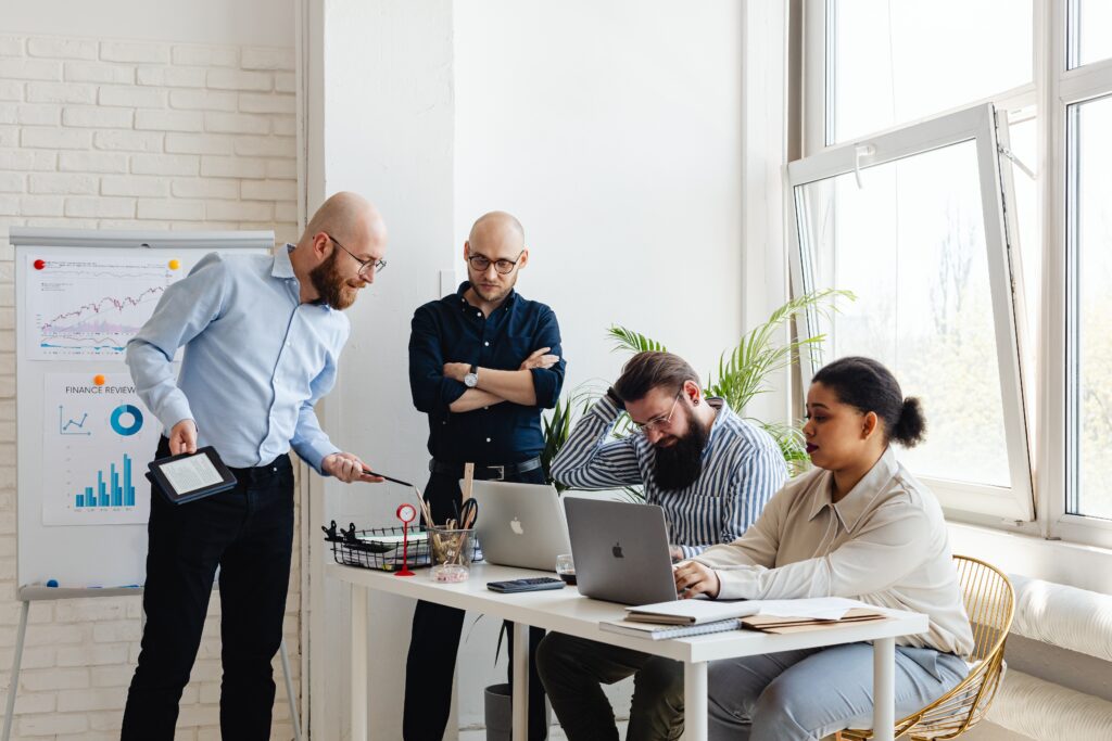 A group of people sitting around a table with laptops.