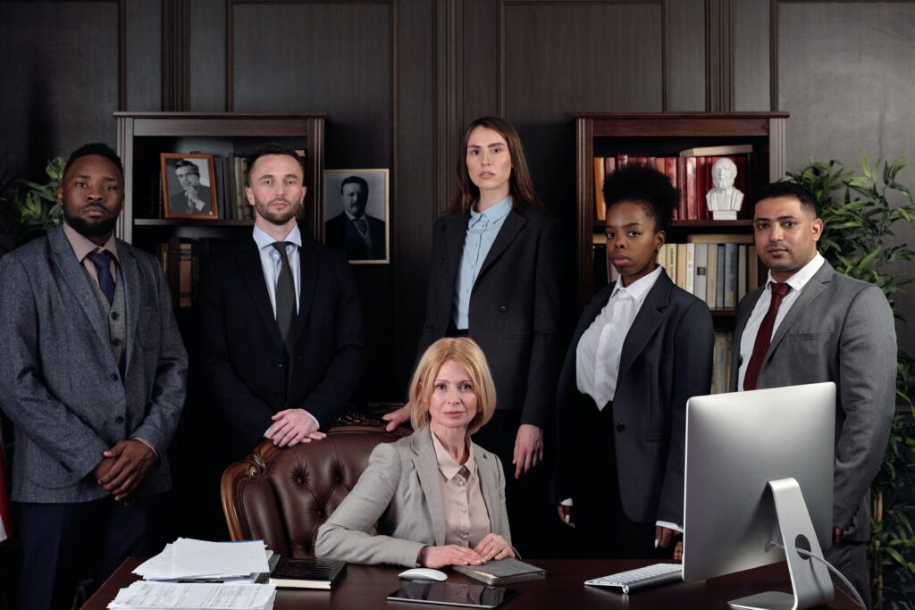 A group of people in suits and ties standing around a desk.