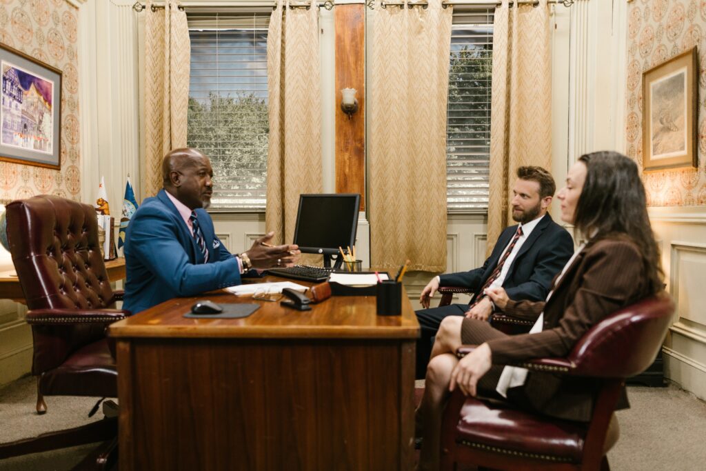 A group of people sitting around a wooden desk.